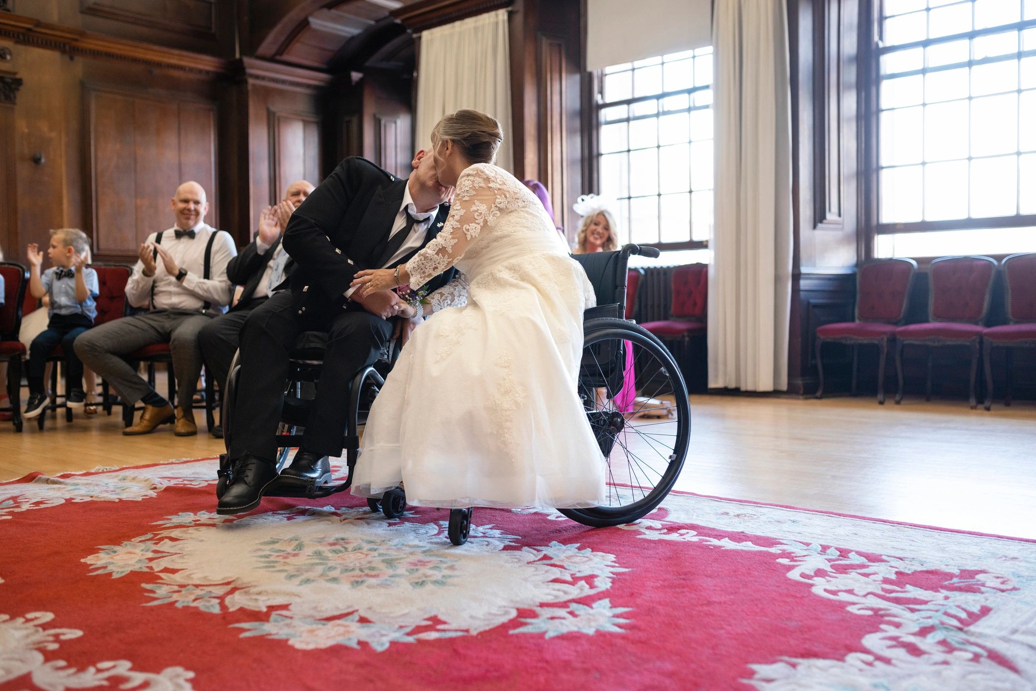 Newly married couple sharing a kiss while guests celebrate