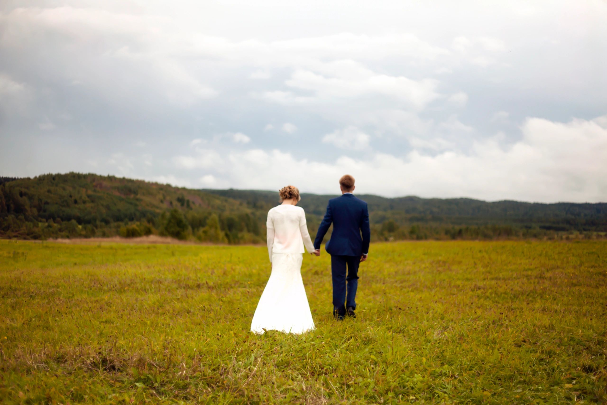 Bride and groom walking hand in hand in a field